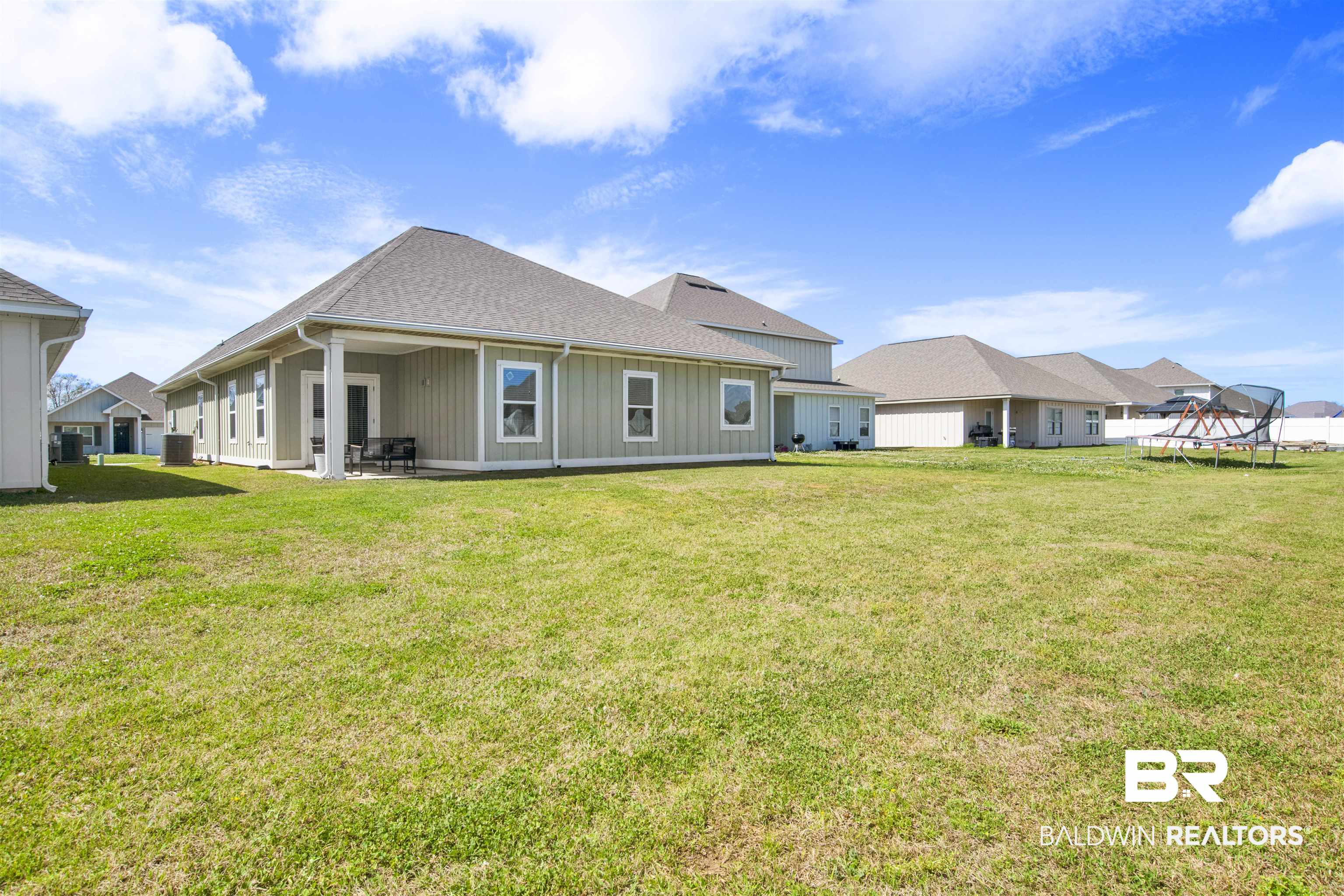 24253 Alydar Loop Daphne, AL 36526 - Photo 38 of 44 Back of house with a trampoline, a patio, a yard, roof with shingles, and board and batten siding