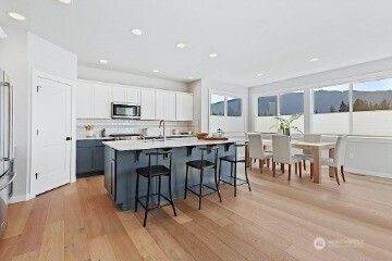 33632 Northeast 42nd Street Carnation, WA 98014 - Photo 11 of 28 a open kitchen with stainless steel appliances granite countertop a stove a refrigerator a microwave a dining table and chairs with wooden floor