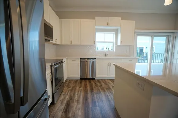 a kitchen with wooden floors and white stainless steel appliances