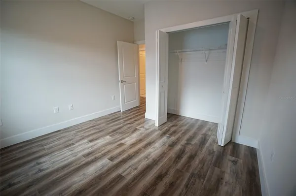 a view of an empty room with wooden floor and closet