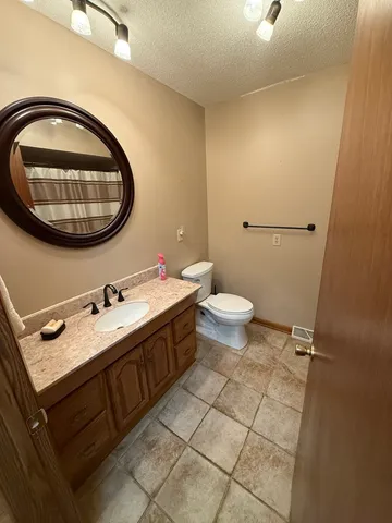 a bathroom with a granite countertop sink a toilet and a mirror
