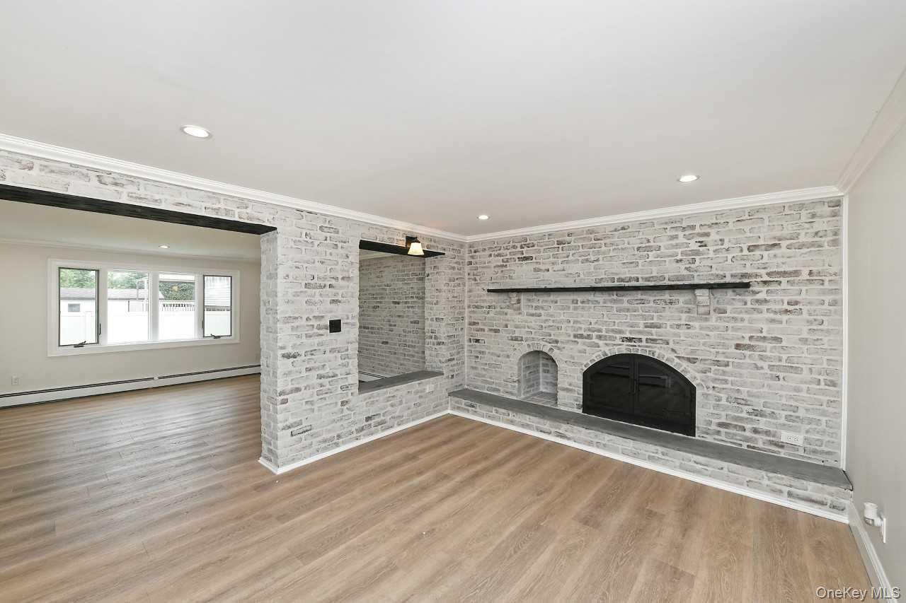107 Beverly Road Massapequa, NY 11758 - Photo 25 of 41 an empty room with wooden floor and fireplace