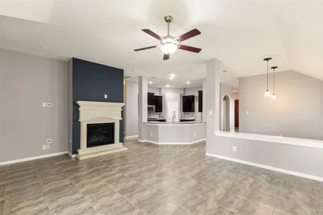 a view of an empty room with a fireplace and a chandelier fan