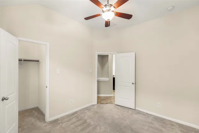 an empty room with closet and a ceiling fan