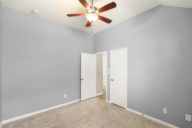 an empty room with closet and a chandelier fan