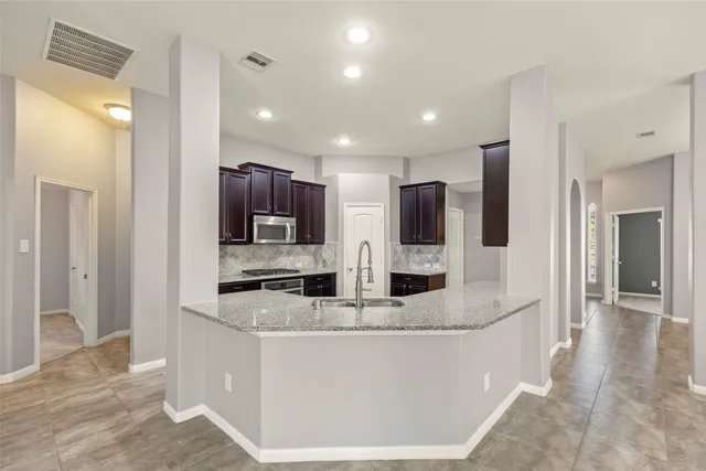 a view of a kitchen with stainless steel appliances kitchen island granite countertop a refrigerator and a sink