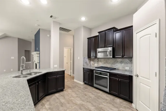 a kitchen with kitchen island granite countertop stainless steel appliances and sink