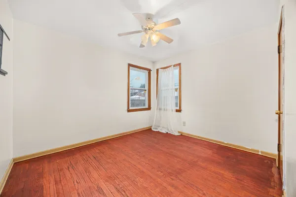 an empty room with a window and a ceiling fan