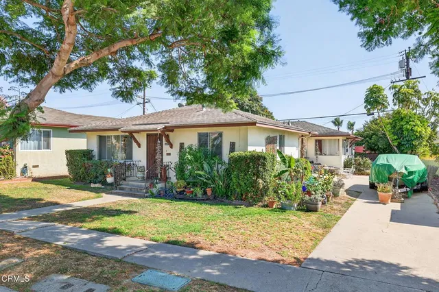 a front view of a house with a yard and potted plants