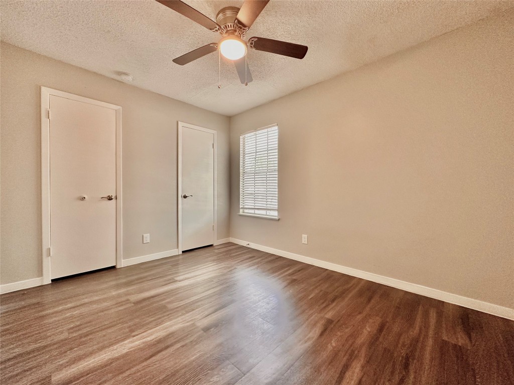 1200 Banister Lane, Unit 4 Austin, TX 78704 - Photo 13 of 15 an empty room with wooden floor chandelier fan and windows