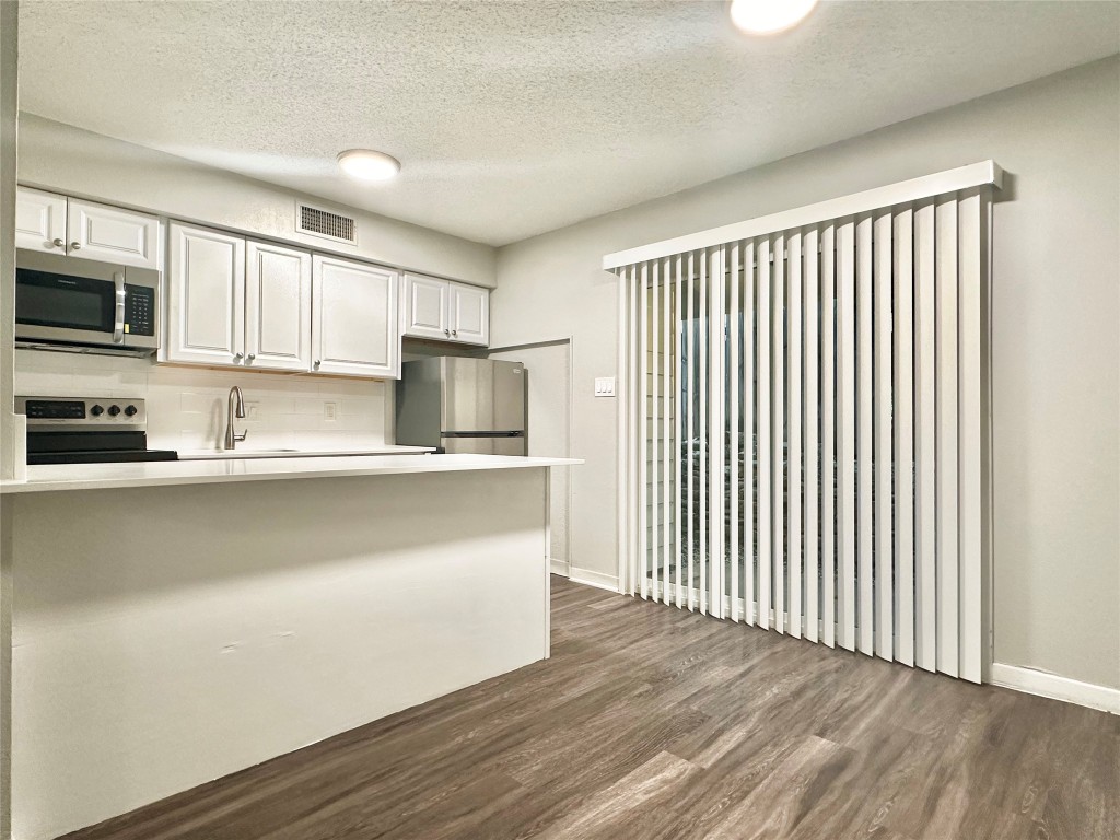 1200 Banister Lane, Unit 4 Austin, TX 78704 - Photo 9 of 15 a kitchen with stainless steel appliances granite countertop a refrigerator a stove top oven a sink and dishwasher with wooden floor
