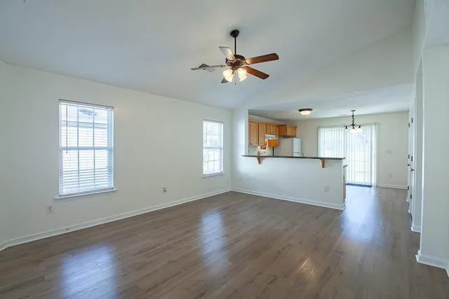 an empty room with wooden floor window and ceiling fan
