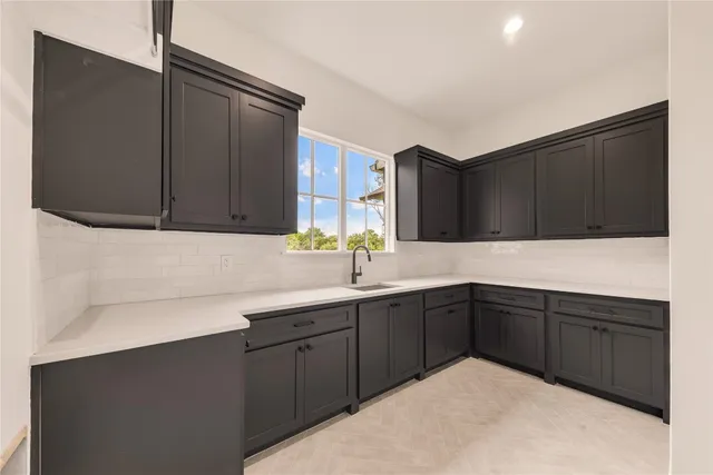 a kitchen with kitchen island granite countertop a sink dishwasher and white cabinets with wooden floor