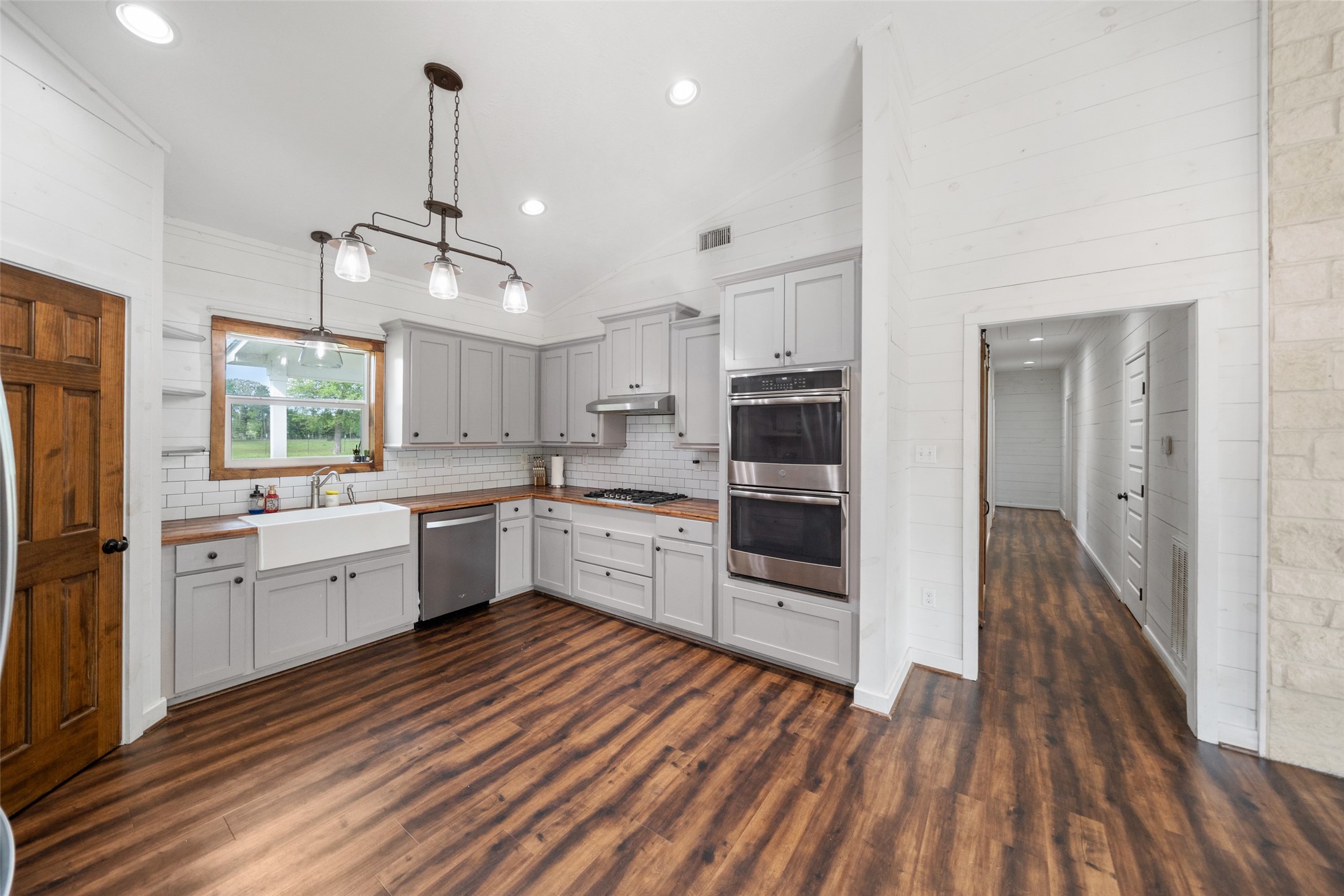 1121 Pelican Road Shepherd, TX 77371 - Photo 11 of 34 Beautifully updated kitchen with custom cabinetry, farmhouse sink, stainless steel appliances, and warm wood countertops, all complemented by shiplap walls and abundant natural light.