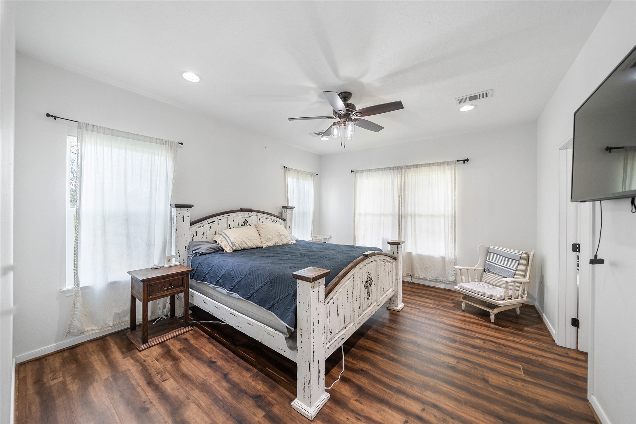 1121 Pelican Road Shepherd, TX 77371 - Photo 18 of 34 Spacious primary bedroom with wood-look flooring, abundant natural light, and a peaceful, airy feel—perfect for relaxing at the end of the day.