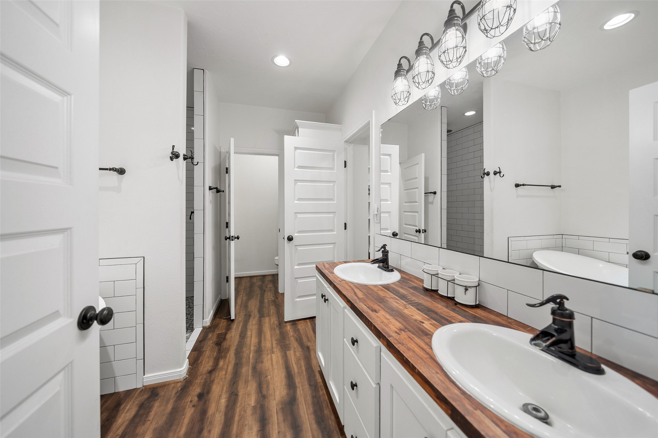 1121 Pelican Road Shepherd, TX 77371 - Photo 19 of 34 Well-appointed primary bath with dual sinks, wood countertops, stylish lighting, and a walk-in shower, offering a clean and modern farmhouse feel.