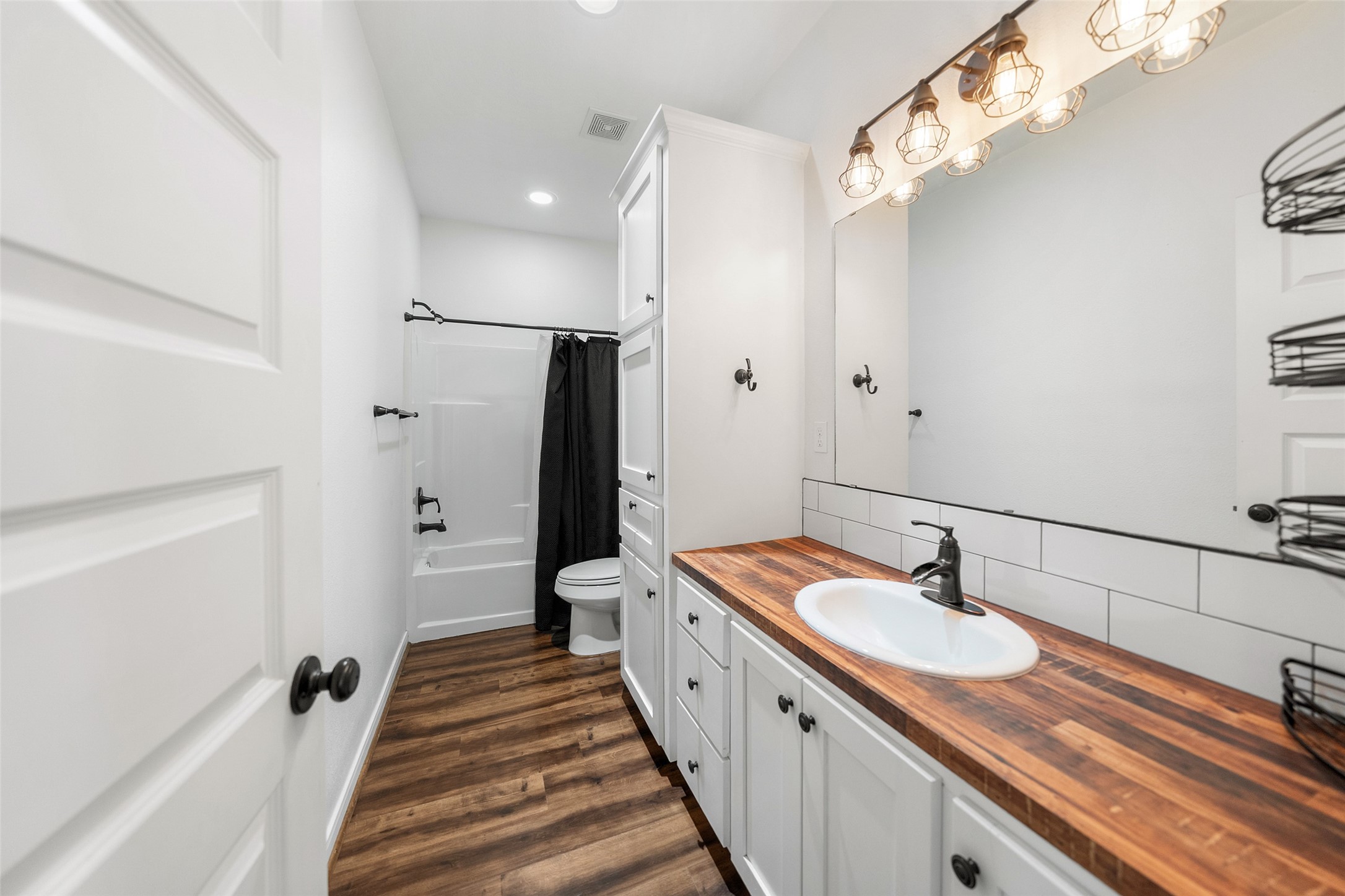 1121 Pelican Road Shepherd, TX 77371 - Photo 22 of 34 Stylish secondary bathroom featuring a wood countertop vanity, updated lighting, and a tub/shower combo with clean, modern finishes.