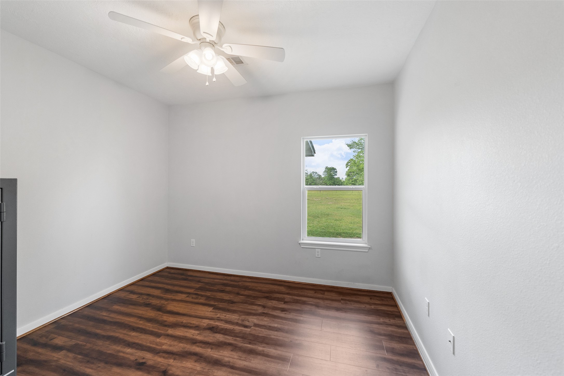 1121 Pelican Road Shepherd, TX 77371 - Photo 23 of 34 Additional bedroom with wood-look flooring, ceiling fan, and a window offering natural light and serene outdoor views.