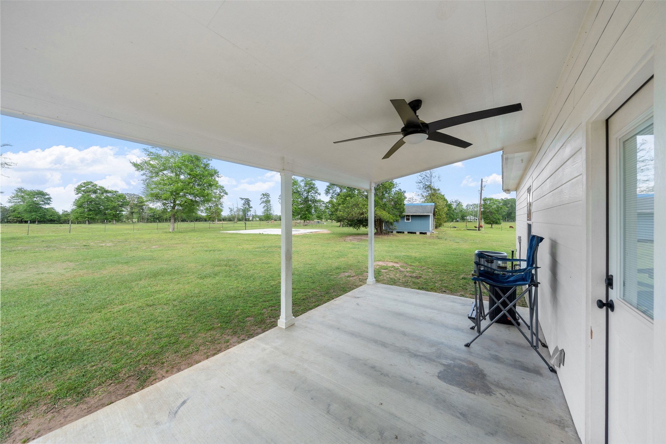 1121 Pelican Road Shepherd, TX 77371 - Photo 24 of 34 Covered back patio with ceiling fan, offering a peaceful spot to relax and enjoy expansive country views and open green space.