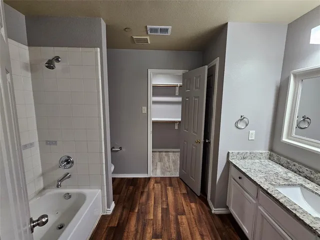 a bathroom with a granite countertop tub sink and wooden floor