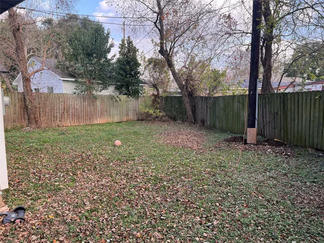 a view of a backyard with large trees and wooden fence