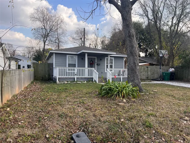 a view of a house with a yard and large tree