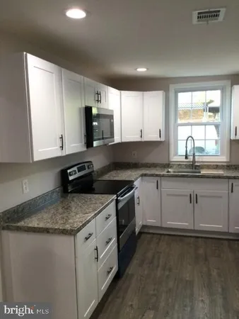 a kitchen with granite countertop a sink stove and cabinets
