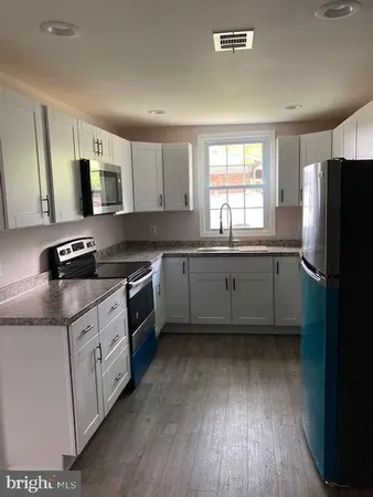 a kitchen with stainless steel appliances granite countertop a sink cabinets and wooden floor