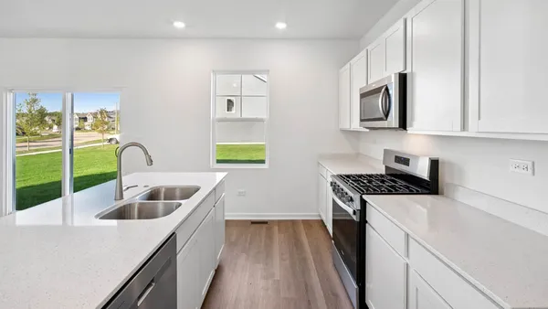 a kitchen with white cabinets a sink a stove and a wooden floor