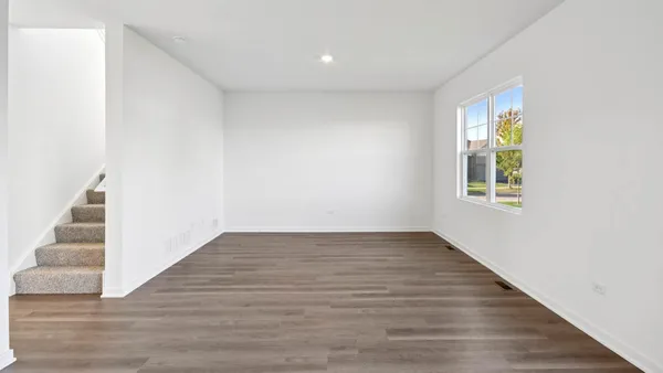 a view of an empty room with wooden floor and stairs
