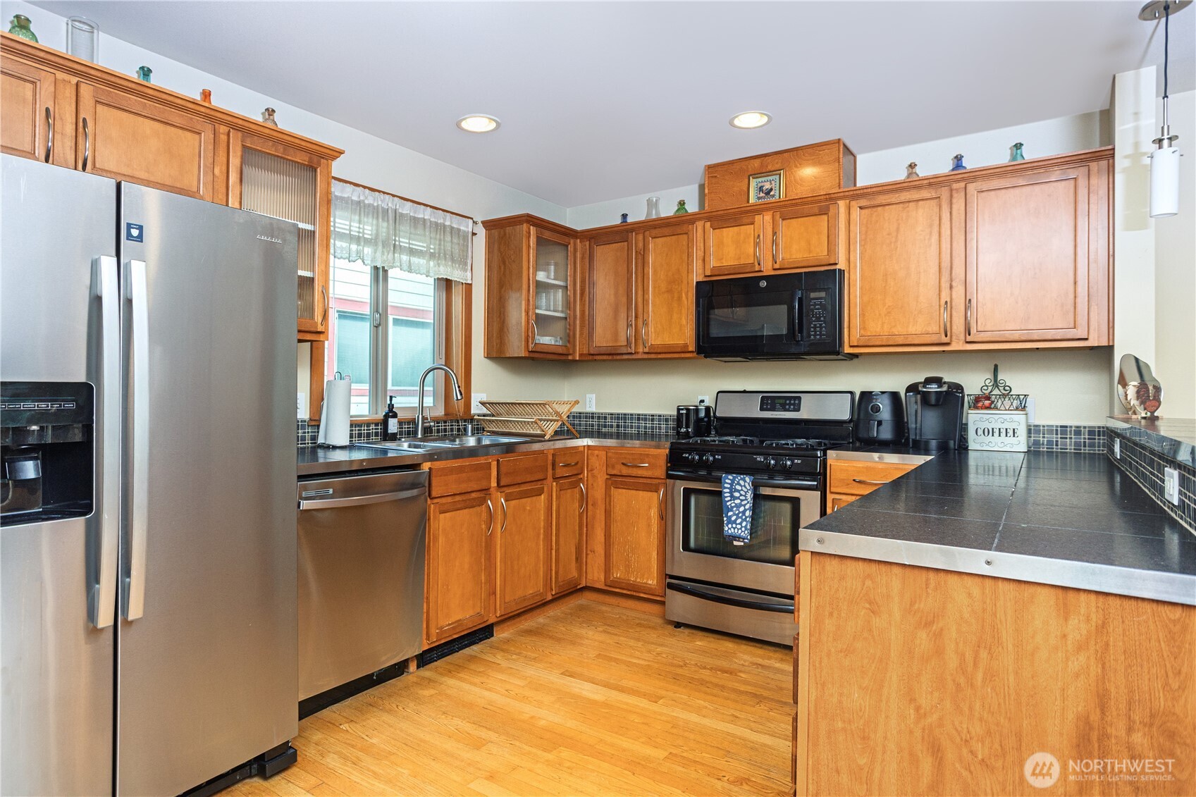 3314 Wetmore Avenue South, Unit B Seattle, WA 98144 - Photo 10 of 28 a kitchen with stainless steel appliances granite countertop a refrigerator a stove top oven a sink and dishwasher
