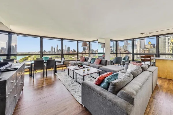 a living room with furniture kitchen view and a wooden floor