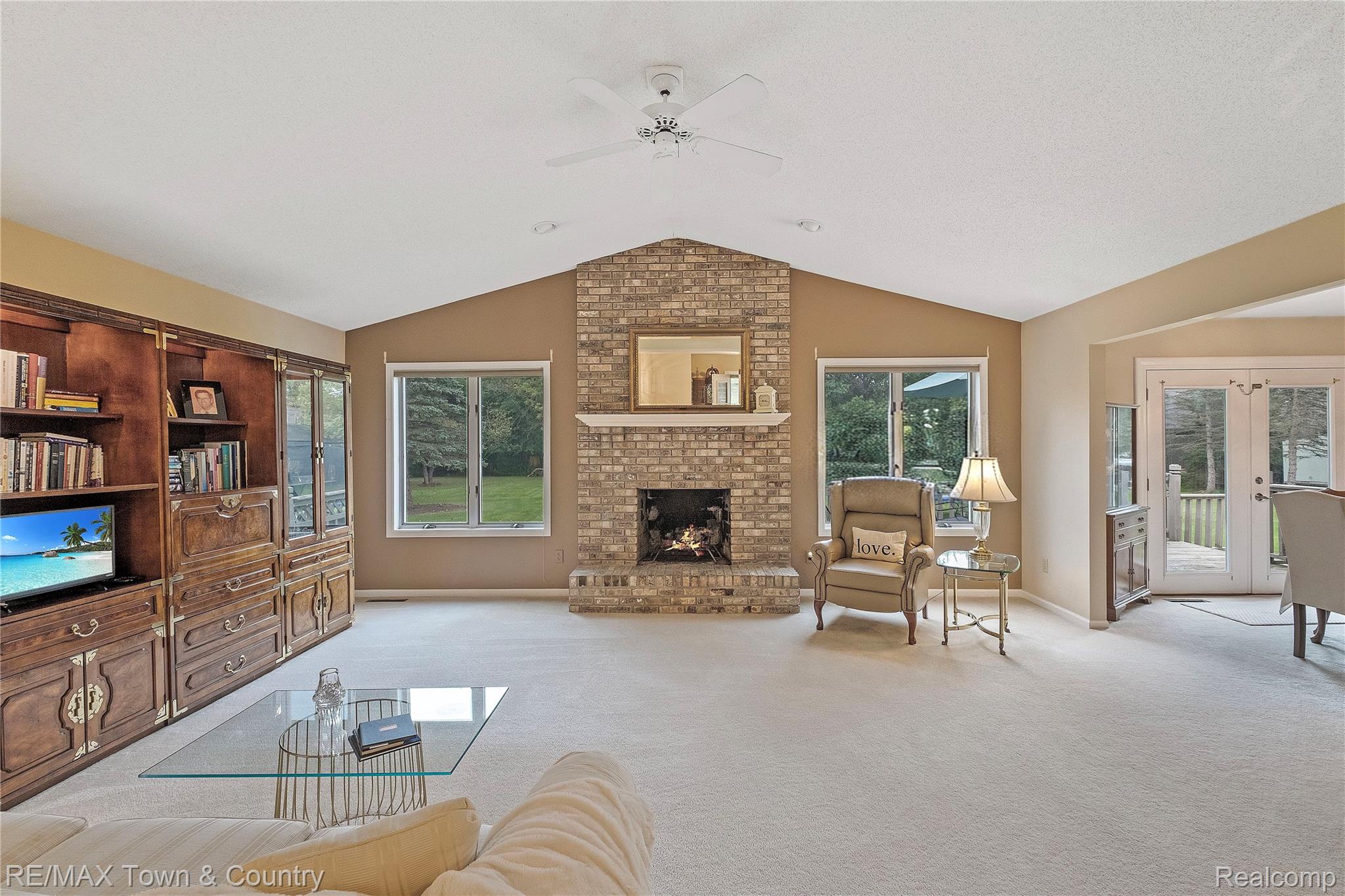 5464 North Seymour Road Flushing, MI 48433 - Photo 9 of 45 Expansive living area with vaulted ceilings, a brick fireplace, built-in wooden cabinetry, and French doors leading to an outdoor deck