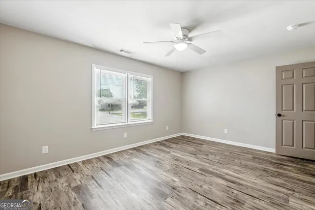 a view of an empty room with wooden floor and a window