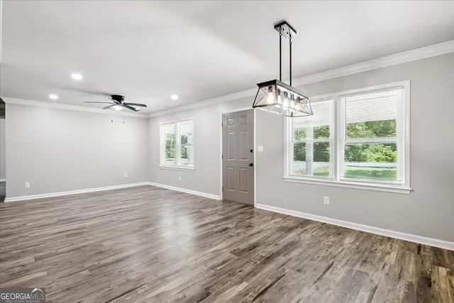 an empty room with wooden floor chandelier and windows