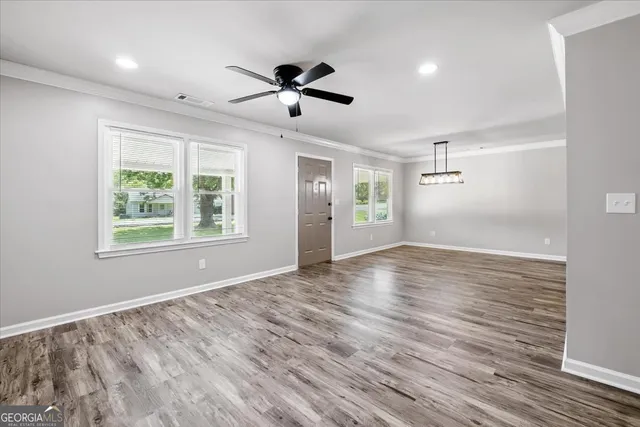 a view of empty room with wooden floor and fan