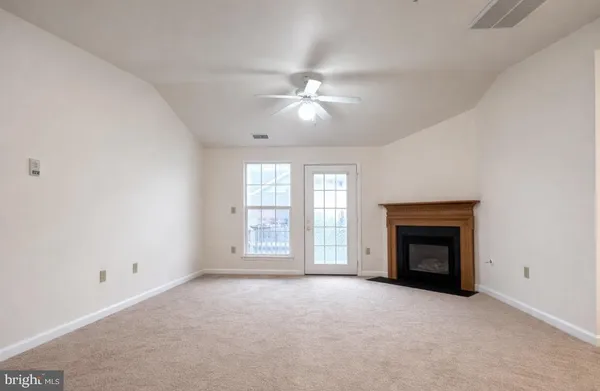 an empty room with a fireplace and a ceiling fan