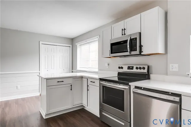 a kitchen with cabinets stainless steel appliances and wooden floor