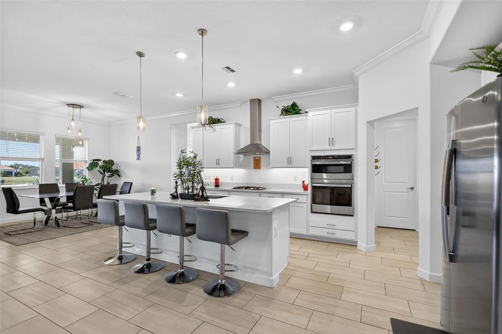 17109 Star Banks Street Wimauma, FL 33598 - Photo 9 of 60 a view of a kitchen with kitchen island stainless steel appliances a stove a sink a table and chairs