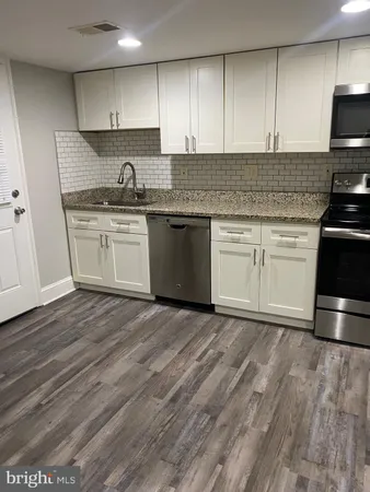 a kitchen with granite countertop a sink stainless steel appliances and cabinets