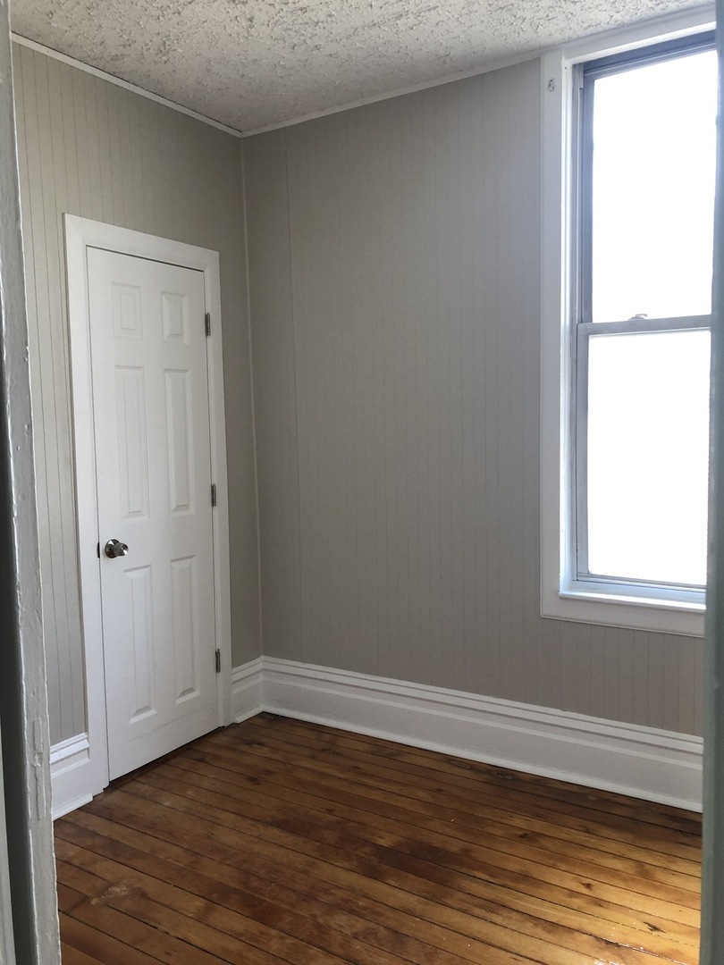 827 West 33rd Place, Unit 2F Chicago, IL 60608 - Photo 14 of 23 a view of an empty room with wooden floor and a window