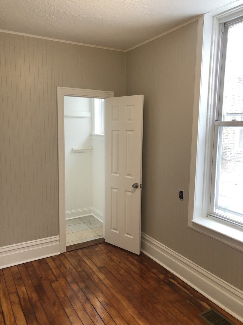 827 West 33rd Place, Unit 2F Chicago, IL 60608 - Photo 15 of 23 an empty room with wooden floor and windows