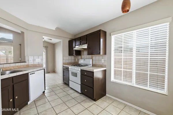 a kitchen with stainless steel appliances granite countertop a stove top oven a sink dishwasher and a refrigerator