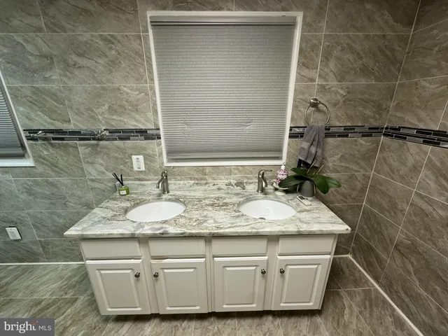 a bathroom with a granite countertop sink a mirror and shower