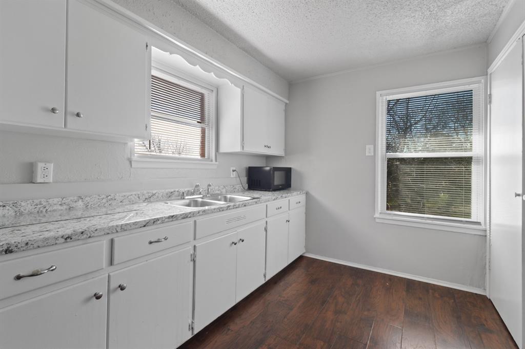 a room with granite countertop cabinets stainless steel appliances a sink and a window
