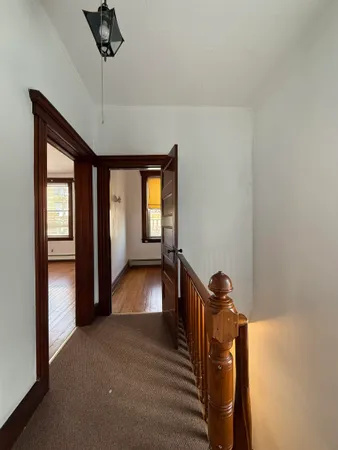 a view of a hallway with wooden floor and chandelier