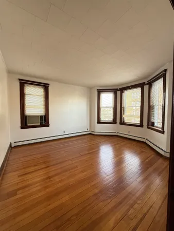 a view of an empty room with wooden floor and fan