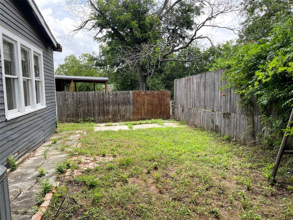613 Northwest 5th Street Mineral Wells, TX 76067 - Photo 33 of 34 a view of a backyard with a large tree and wooden fence