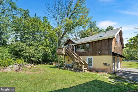 a house that is sitting in the grass with large trees