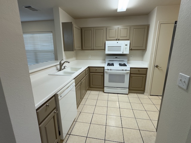 109 Plover Pass Georgetown, TX 78633 - Photo 24 of 25 Kitchen with light countertops, white appliances, a textured wall, gray cabinetry, and light tile patterned floors